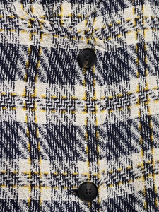 Gros plan sur la texture du tweed à carreaux bleu marine et jaune avec boutons noirs