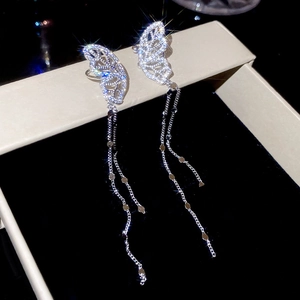 Macro shot of sparkling zircon butterfly earrings with long chain tassels on velvet