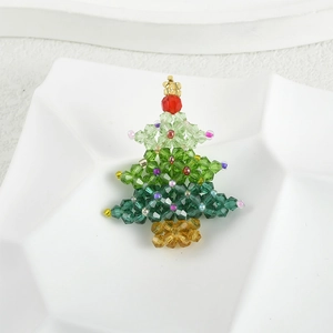 Detail view of handmade crystal beaded Christmas tree pendant in a white ceramic plate