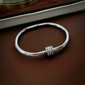 Close-up of silver stainless steel bangle with three parallel rows of cubic zirconia stones