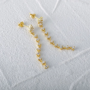 Detailed view of long gold tassel earrings with glittering small zircon stone links
