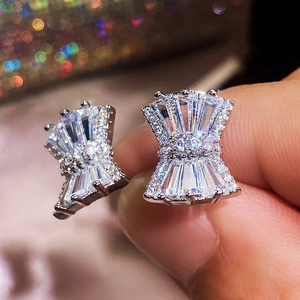 Close-up of sparkling silver bow earrings set with clear zircon stones on hand