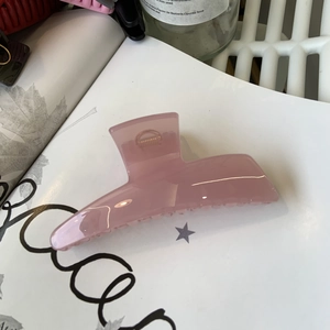 Pink translucent acrylic shark hair claw clip on fashion book in natural light