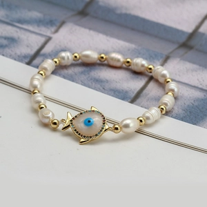Detailed close-up of freshwater pearl bracelet with golden evil eye fish pendant
