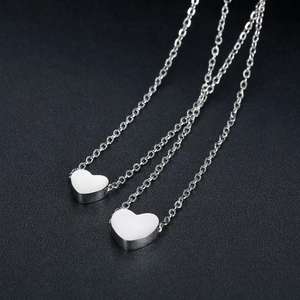 Close-up of dual silver stainless steel heart necklaces with polished mirror finish