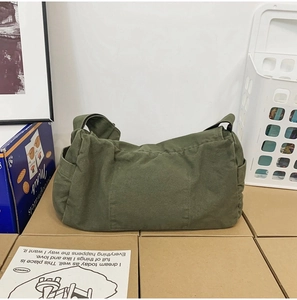 Detail of green washed canvas messenger bag featuring a front pocket and durable texture