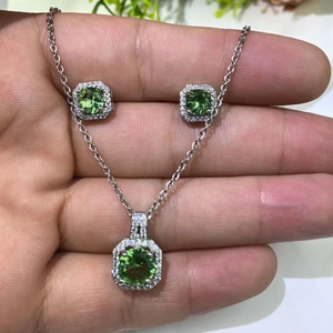 Close-up of green round gemstone necklace and matching earrings set in silver finish