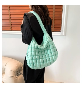 Detail of mint green quilted puffer bag with textured bubble design worn over the shoulder