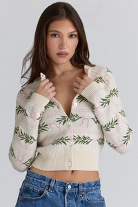 Close-up of knit cardigan showing festive green leaf and pink ribbon jacquard details