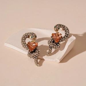 Detailed view of snake earrings with amber triangle stones and green gem accents