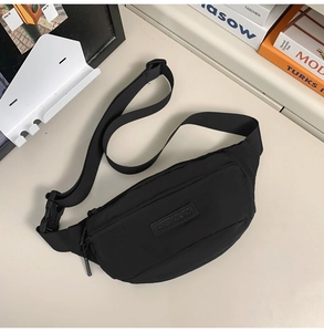 Close-up of black nylon chest bag with adjustable strap and plastic buckle on a desk