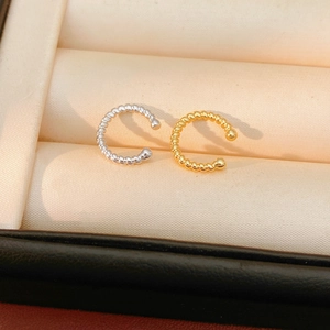 Close-up of twisted rope ear cuffs in 18k gold and silver finish on a fabric liner