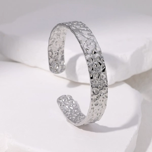 Bracciale rigido aperto con trama martellata irregolare su fondo in pietra bianca