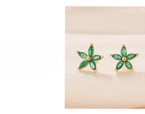Detailed macro view of 925 silver flower stud earrings with green zircon petals and gold plating