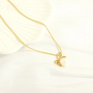 Detailed close-up of a golden freshwater pearl pendant necklace with a diamond bow