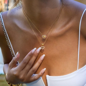 Close-up of 18K gold stainless steel layered heart necklace with crystals on a model