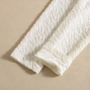 Nahaufnahme der weißen Ärmelmanschette mit elegantem Jacquard-Blumenmuster