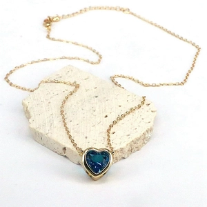 Dettaglio della catena dorata con ciondolo a cuore in zircone blu scuro su pietra