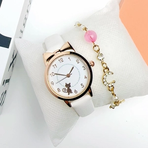 Detail of white cat dial watch with gold star and moon bracelet set on display pillow