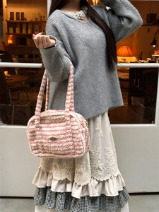 Close-up of pink and white striped plush handbag featuring a central metal logo plate