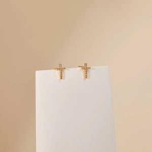 Macro detail of cross stud earrings with sparkling white zircons in 18K gold plating