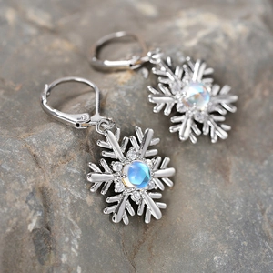 Macro des boucles d'oreilles flocon avec pierre de lune bleue et zircons sur roche grise