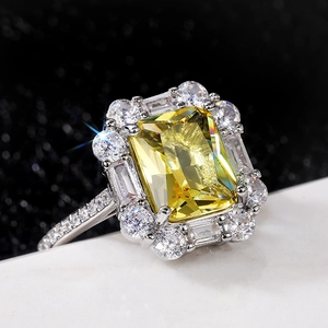 Macro shot of luxury ring with large yellow emerald-cut stone and diamond halo