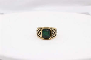 Macro shot of Viking Celtic totem ring with emerald-cut green gemstone in gold finish
