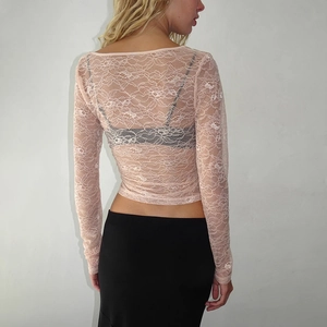 Détail du haut court en dentelle rose transparente, vue de dos montrant les motifs floraux