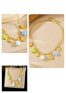 Detail of gold starfish and turtle charms on a paperclip chain necklace for summer