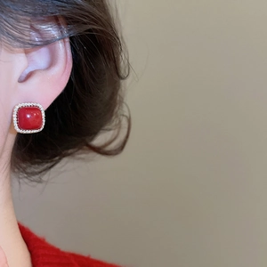 Close-up of red square zircon earring with pavé crystal border worn by a model