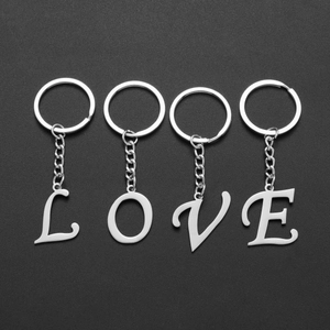 Close-up of four silver stainless steel keychains with LOVE letter pendants on black background