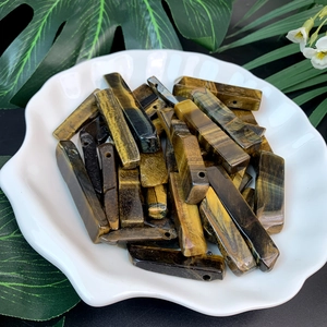 Macro detail of natural Tiger Eye stone columns in a shell ceramic plate with green leaves