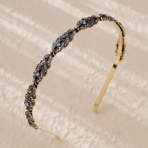 Detail of a gold wheat leaf headband featuring sparkling blue rhinestones on fabric