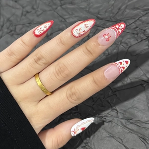 Almond French press-on nails with red hearts, bows, and pearls on a dark background