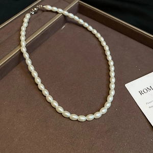 Detail of elegant pearl necklace with oval beads and spherical clasp on velvet tray