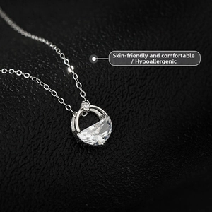 Macro shot of silver minimalist necklace with a semi-circular crystal in an open ring pendant