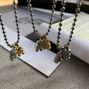 Detail of three titanium steel ball chain necklaces with pave bear pendants in gold and silver