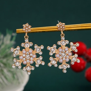 Detail of snowflake earrings with rhinestones and pearls on a festive green background
