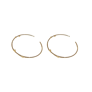 Polished gold circular hoop earrings with geometric triangle rivets on white background