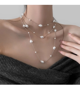 Close-up of elegant layered baroque pearl necklace with fine silver chains on a model
