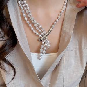 Close-up of multi-layer pearl necklace with silver branch pendant on a model
