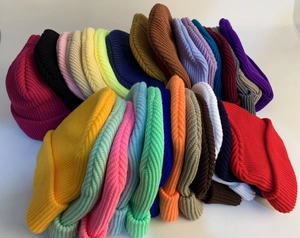 Detailed view of various solid color ribbed knit beanies stacked in multiple vibrant colors