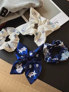 Detailed view of sea-themed embroidery on silk satin bow and scrunchie set