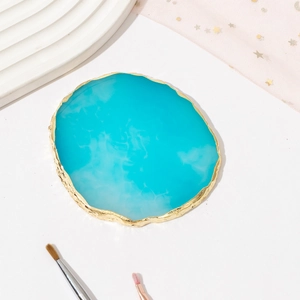 Detailed macro shot of blue resin agate nail palette with gold trim on white ripple tray