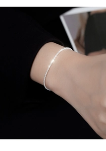 Macro shot of minimalist S925 sterling silver shimmering chain bracelet on woman wrist