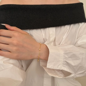 Detail of a minimalist gold S925 silver bracelet with white opal beads on a wrist