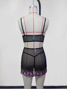 Detail of sheer black mesh lingerie set with floral embroidery on mini skirt back