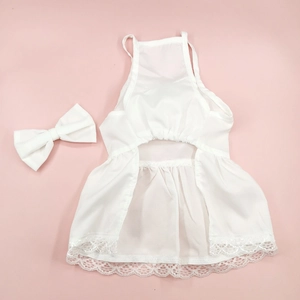 Detailed shot of white satin pet dress with lace hem and matching bow on pink background