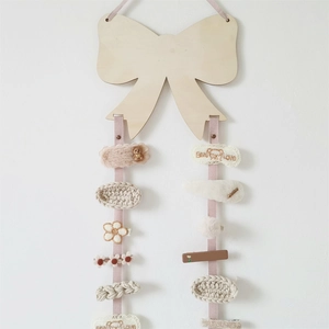 Detail of wooden bow-shaped hair clip organizer with pink ribbons and cute accessories